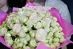 A huge bouquet of white roses `With the birth of a daughter` in pink wrapping paper.