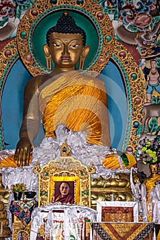 Huge buddha golden statue decorated with religious flags and offerings at evening