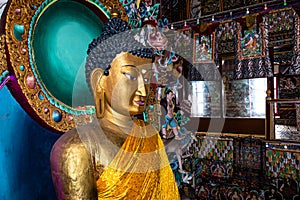 Huge buddha golden statue decorated with religious flags and offerings at evening