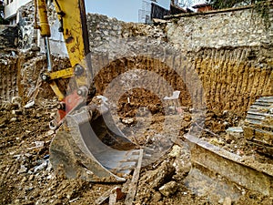 Huge bulldozer shovel head working among the dirt and mud of excavation site while digging on the construction place