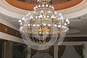 Huge chandelier in the hall. Chandelier on decoarted ceiling of a ballroom