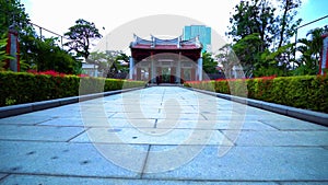 A Huge Chinese gate with a red rooftop between the beautiful garden flower inside the Chinese temple