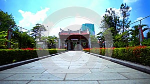 A Huge Chinese gate with a red rooftop between the beautiful garden flower inside the Chinese temple