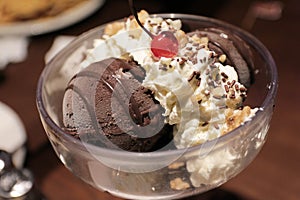 Huge Chocolate ice cream in a bowl with whipping cream and cherry on top