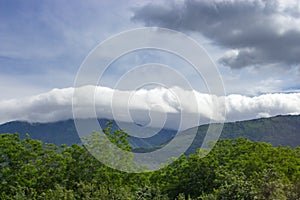 Huge clouds over mountains with green trees forehead. Nature and element concept. Storm background.