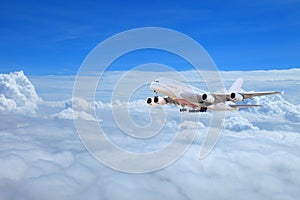 Huge commercial airplane flying above clouds in dramatic sunset