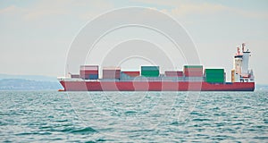 Huge container tanker ship carrying truck size colourful containers in deep blue open ocean sea