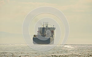 Huge container tanker ship carrying truck size colourful containers in deep blue open ocean sea