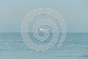 Huge container tanker ship carrying truck size colourful containers in deep blue open ocean sea