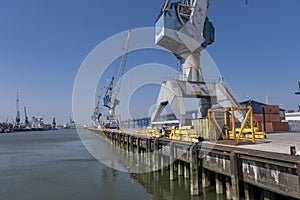 Huge cranes and ships anchored at harbor. International commercial port, city of Rotterdam background. Logistics business