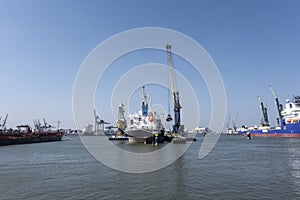 Huge cranes and ships anchored at harbor. International commercial port, city of Rotterdam background. Logistics business