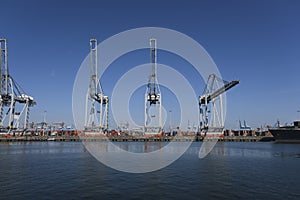 Huge cranes and ships anchored at harbor. International commercial port, city of Rotterdam background. Logistics business