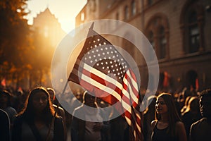 A huge crowd of people marches along a city street with American flags. The Stars and Stripes flutter over people's