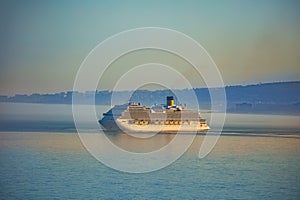 Huge cruise ship at sunset with Spanish coast on background