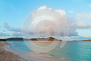 A huge cumulus cloud over sandy beach on tropical island at sunset.