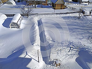 Huge drifts of snow at their summer cottage. The greenhouses are completely covered in snow. Snow covered vegetable garden in the