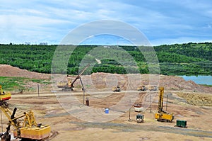 Huge excavators with electric shovel working in the quarry. Big dump trucks transport of minerals in the limestone open-pit mining