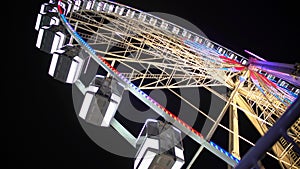 Huge Ferris wheel with illuminated passenger cars rotating fast, amusement ride