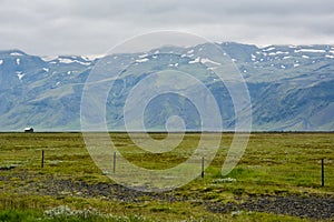 Huge green empty field with view to mountain and small house