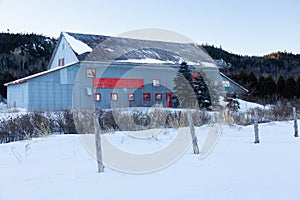 Huge grey metal barn with red trimming seen during an early morning winter,