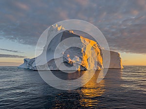 A huge high breakaway glacier drifts in the southern ocean off the coast of Antarctica at sunset, the Antarctic