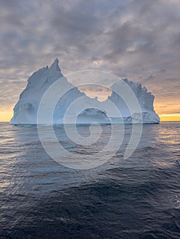 A huge high breakaway glacier drifts in the southern ocean off the coast of Antarctica at sunset, the Antarctic