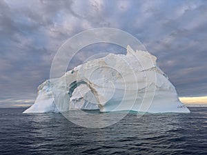 A huge high breakaway glacier drifts in the southern ocean off the coast of Antarctica at sunset, the Antarctic