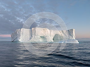 A huge high breakaway glacier drifts in the southern ocean off the coast of Antarctica at sunset, the Antarctic