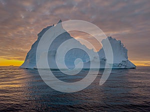 A huge high breakaway glacier drifts in the southern ocean off the coast of Antarctica at sunset, the Antarctic