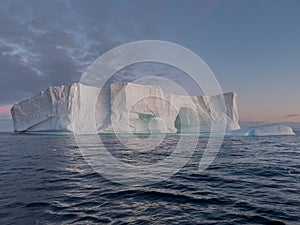 A huge high breakaway glacier drifts in the southern ocean off the coast of Antarctica at sunset, the Antarctic