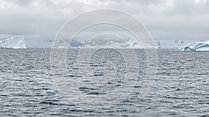 A huge high breakaway glacier is passing by in the southern ocean off the coast of Antarctica, the Antarctic Peninsula