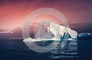 The huge iceberg on the colorful sky background.