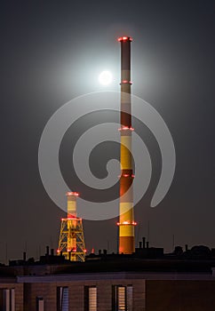 Huge industrial chimneys lit by a full moon