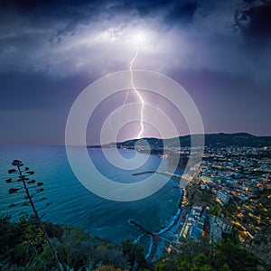 Huge lightning from dark stormy sky strikes coastal city