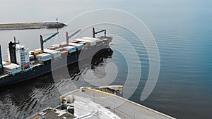 Huge loaded container ship departs modern port in summer