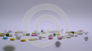 Huge number of different kinds pills falling on white background in slow motion.