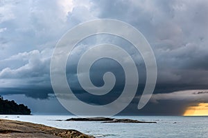 Huge offshore thunder storm and rain at sunset over a tropical ocean