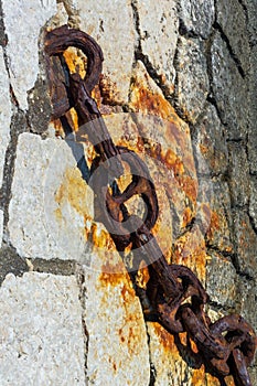 Huge old rusty chain on the stones of the pier