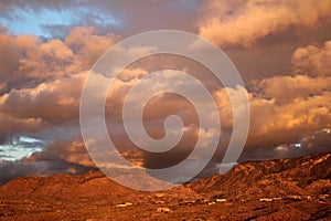 Huge orange monsoon clouds over the deep amber mountains at sunset in Tucson Arizona