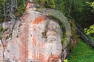 A huge piece of rock with streaks of red and white, bridge leading upwards