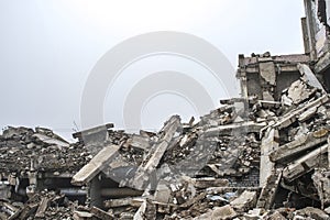 A huge pile of gray concrete debris from piles and stones of the destroyed building. The impact of the destruction