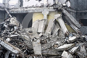 A huge pile of gray concrete debris from piles and stones of the destroyed building. The impact of the destruction