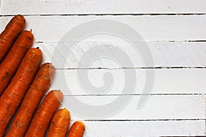 A huge pile of very large fresh and sweet carrots on a white wooden table. beautiful fresh market organic carrots in a