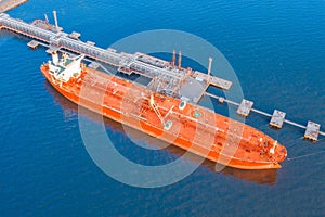 Huge red marine tanker ship, with oil moored to load oil products and export to distant countries across the ocean