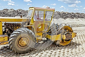 Huge road roller with spikes is compacting soil at construction