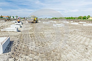 Huge road roller with spikes is compacting soil at construction