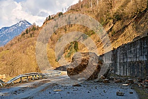 A huge rock fell from the mountains onto the road, destroying the asphalt and blocking half of the roadway