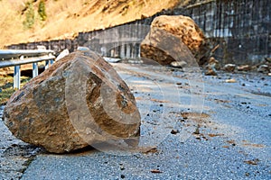 A huge rock fell from the mountains onto the road, destroying the asphalt and blocking half of the roadway