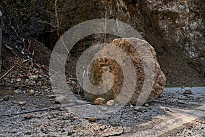 A huge rock fell from the mountains onto the road, destroying the asphalt and blocking half of the roadway