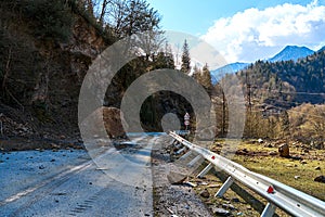 A huge rock fell from the mountains onto the road, destroying the asphalt and blocking half of the roadway